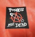 Квадратна черна рок нашивка Punk’s Not Dead с червен символ за анархия и безопасна игла